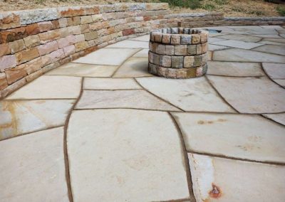 stone patio with fireplace and retaining wall